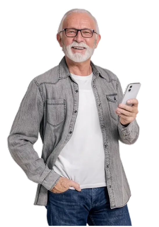 Foto de hombre adulto mayor con barba blanca y lentes sonriendo mientras sostiene un teléfono celular, vistiendo camisa gris sobre camiseta blanca y jeans, sobre fondo negro.